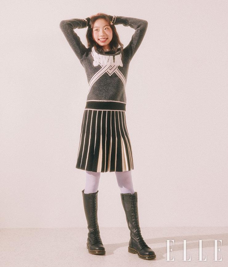 연정이 입은 니트 톱과 니트 플리츠스커트는 모두 Off-White™. 블랙 레이스업 롱부츠는 Dr. Martens. 실버 초커는 Pandora. 양쪽에 찬 진주 브레이슬렛은 모두 Vintage Hollywood. 