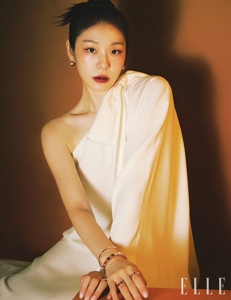 핑크골드에 0.4캐럿 다이아몬드를 세팅한 ‘젬 디올’ 이어링, 오른손에 착용한 핑크골드에 0.22캐럿 다이아몬드를 세팅한 ‘젬 디올’ 브레이슬릿, 핑크골드에 1.75캐럿 다이아몬드를 세팅한 와이드 버전 ‘젬 디올’ 브레이슬릿, 검지에 낀 핑크골드에 0.50캐럿 다이아몬드를 세팅한 ‘젬 디올’ 링, 약지에 낀 핑크골드에 0.14캐럿 다이아몬드를 세팅한 ‘젬 디올’ 링, 왼손 약지에 착용한 핑크골드 ‘젬 디올’ 링은 모두 Dior Joaillerie. 원 숄더 드레스는 Dior.