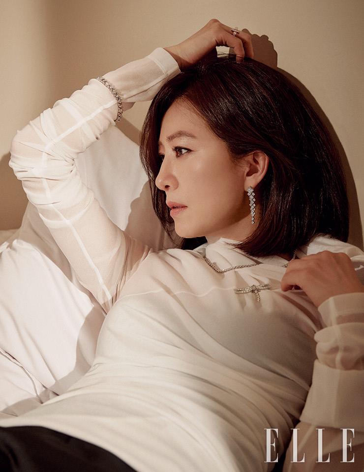 사각 모티프의 티파니 다이아몬드 드롭 이어링, 플래티넘 소재에 다이아몬드를 세팅한 티파니 빅토리아 그레듀에이티드 라인 네크리스, 잠자리 모양의 티파니 인챈트 드래곤플라이 브로치, 오른쪽 손목의 플래티넘 소재 티파니 프린세스 컷 다이아몬드 브레이슬렛, 약지의 티파니 T1 와이드 풀 다이아몬드 링은 모두 Tiffany & Co. 화이트 톱과 스커트는 모두 Wooyoungmi. 