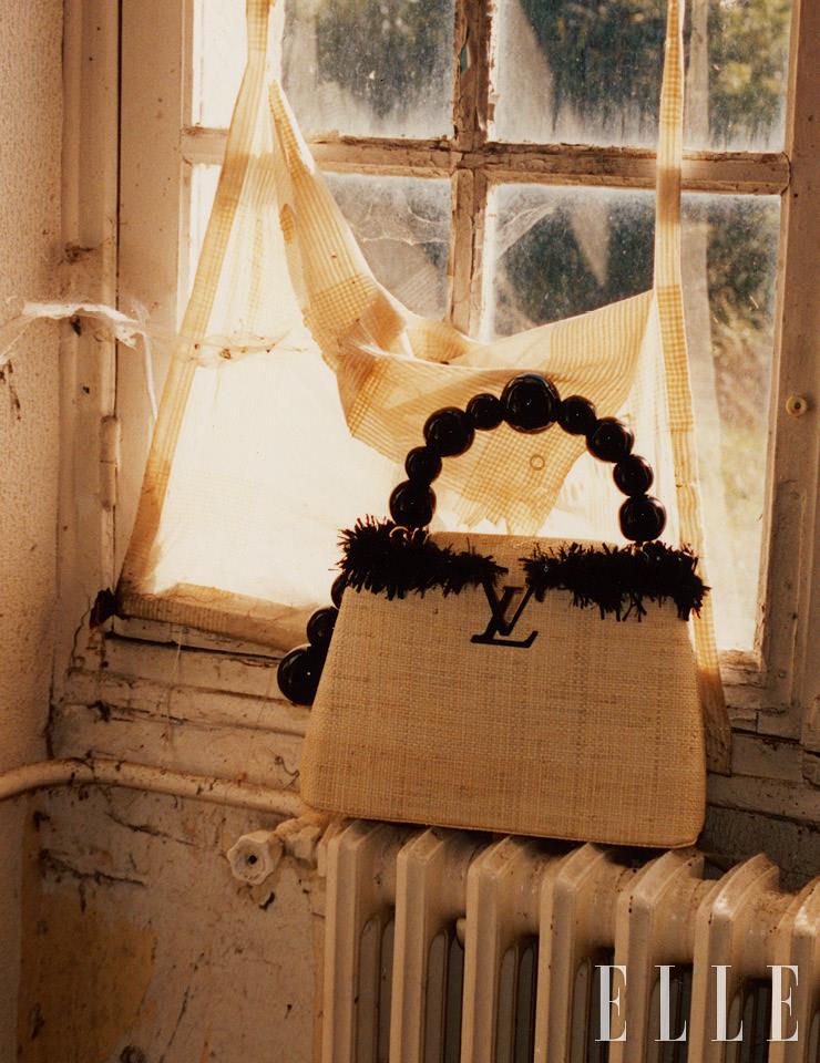 JEAN-MICHEL OTHONIEL_ 파리 베이스의 장-미셸 오토니엘의 아티카퓌신 백은 라피아 소재와 오트 쿠튀르에서 사용하는 블랙 새틴 자수 장식을 더했다. 손잡이는 오토니엘의 작품 파리 팔레 루아얄 지하철역 입구에 설치된 ‘야행자들의 키오스크’를 떠올리게 하는 커다란 레진 비즈를 장식했다. 장-미셸 오토니엘이 완성한 아티카퓌신 백은 Louis Vuitton. 