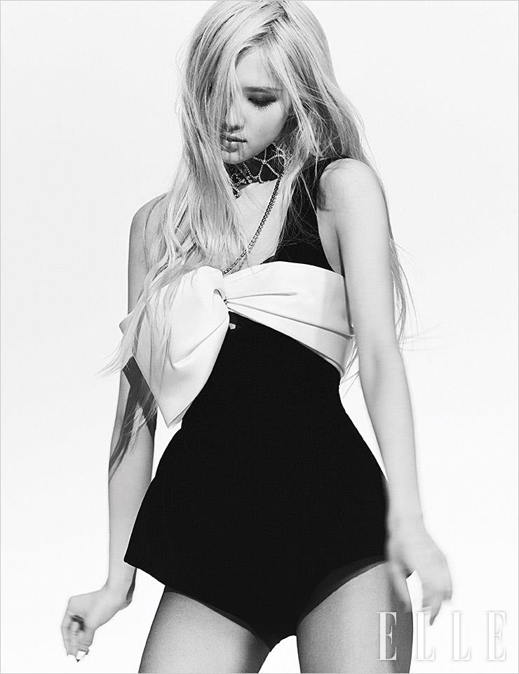 리본 장식이 돋보이는 점프수트와 클로버 펜던트 초커는 모두 Saint Laurent by Anthony Vaccarello.
