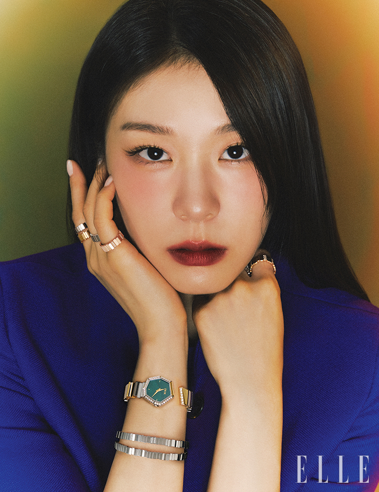 다이얼에 말라카이트 원석을 세팅한 ‘젬 디올’ 타임피스는 Dior Timepiece. 오른손 검지에 착용한 다이아몬드 세팅 버전의 ‘젬 디올’ 화이트골드 링과 옐로골드 링, 약지에 낀 ‘젬 디올’ 화이트골드 링과 새끼손가락에 낀 ‘젬 디올’ 핑크골드 링, 화이트골드에 0.22캐럿 다이아몬드를 세팅한 ‘젬 디올’ 브레이슬릿, 레이어드한 ‘젬 디올’ 화이트골드 브레이슬릿, 왼손에 착용한 옐로골드 ‘젬 디올’ 링은 모두 Dior Joaillerie. 퍼플 컬러의 재킷은 Dior.