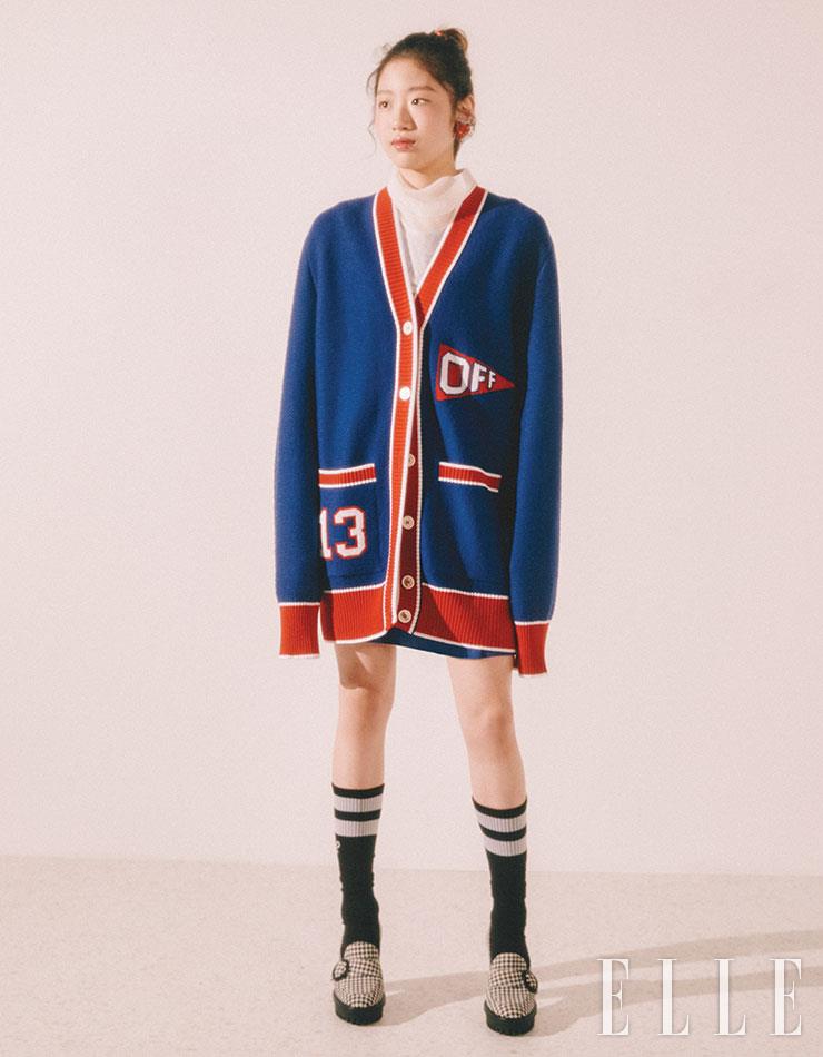 해인이 입은 화이트 메시 풀오버는 D’demoo. 블루 스커트는 Claudie Pierlot. 블루 카디건과 양말은 모두 Off-White™. 하운즈투스 로퍼 힐은 Gianvito Rossi. 하트 비즈 이어링은 Fruta. 