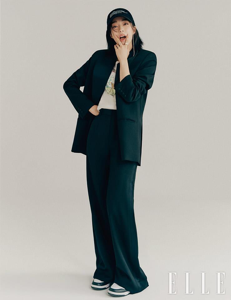 블랙 수트 세트업은 Magda Butrym by Mue. 프린트 티셔츠는 Re/done. 레터링 볼캡과 드롭 이어링은 모두 Verutum. 레이어드한 실버 링은 모두 Ille Lan.