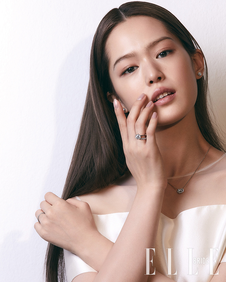 은은하게 반짝이는 이어링은 티파니 플래티늄 솔리테어 이어링, 단아한 펜던트는 티파니 플래티늄 솔리테어 펜던트, 프롱 디자인의 다이아몬드 세팅 링은 티파니 세팅 링, 라운드 브릴리언트 컷 세팅으로 눈부시게 빛나는 티파니 임브레이스 밴드 링, 심플한 밴드 링은 티파니 솔리스트 밴드 링으로 모두 Tiffany&Co. 투명한 오간자를 덧댄 드레스는 Bride And You.