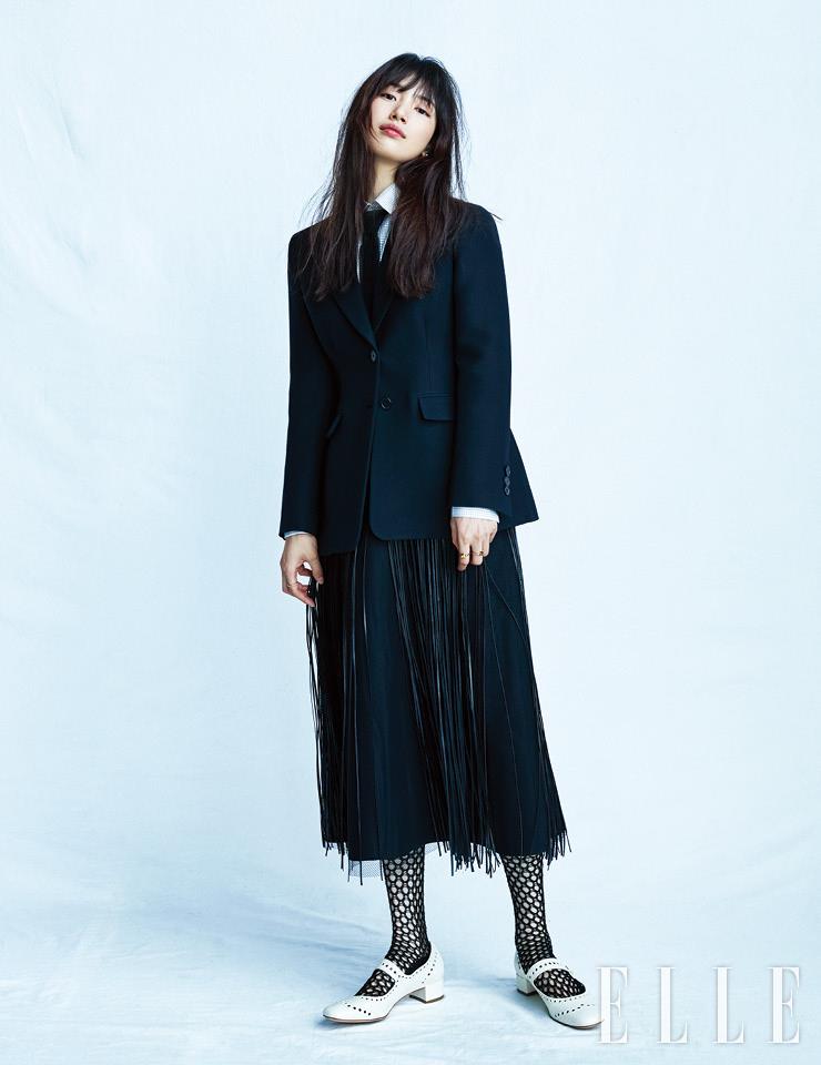 블랙 바 재킷과 프린지 스커트, 체크 셔츠, 피시넷 삭스, 블랙 타이, 화이트 메리 제인 슈즈, 진주 이어링, 양손에 착용한 링은 모두 Dior.