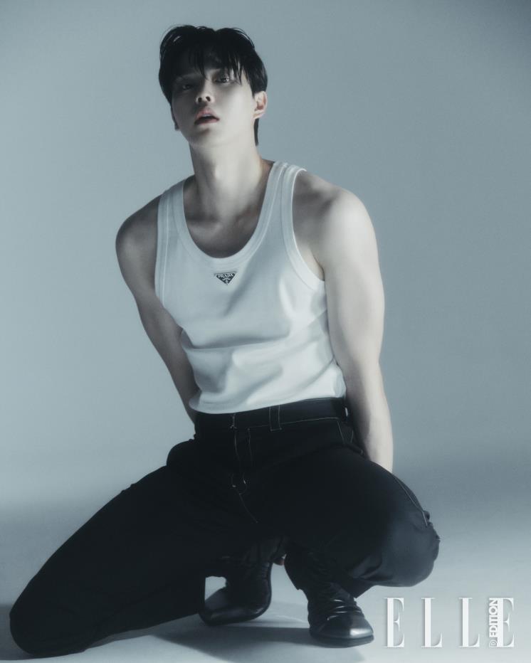 로고 장식의 민소매 톱, 울 소재의 팬츠, 카프 스킨 부츠는 모두 Prada. 