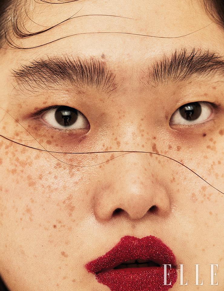 짙은 눈썹과 매력적인 주근깨는 자연스럽게 살리고, 도톰한 입술엔 Gucci Beauty 루즈 아 레브르 매트, 502 에디 스칼렛을 불규칙하게 오버사이즈로 발랐다. 그 위에 아이섀도 브러시를 사용해 비즈 장식을 얹어 자유롭고 사랑스러운 유림의 분위기를 극대화했다.