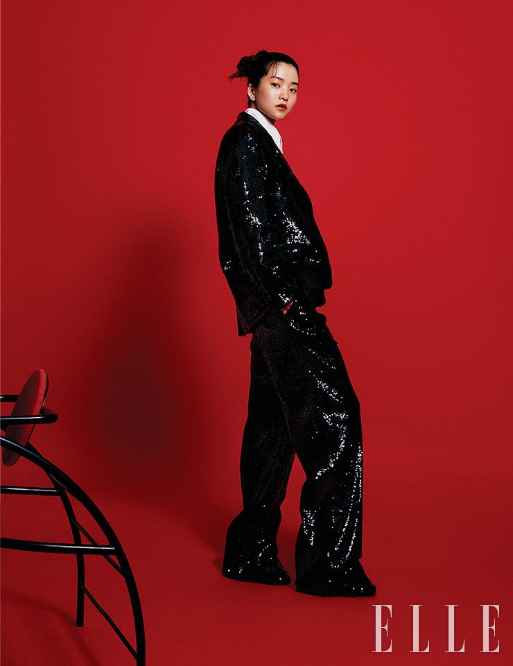 블랙 스팽글 장식의 수트와 화이트 셔츠, 삼각 로고 이어링은 모두 Prada.