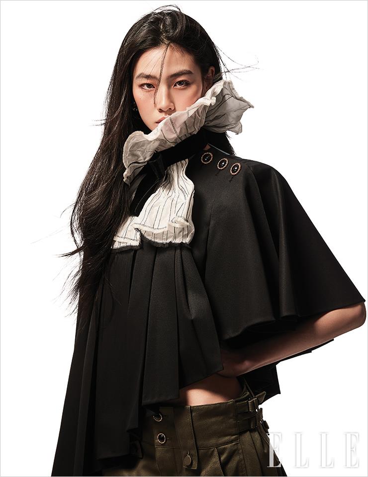 언밸런스한 헴라인의 블랙 케이프와 리본 디테일이 더해진 러플 칼라, 팬츠는 모두 Louis Vuitton.