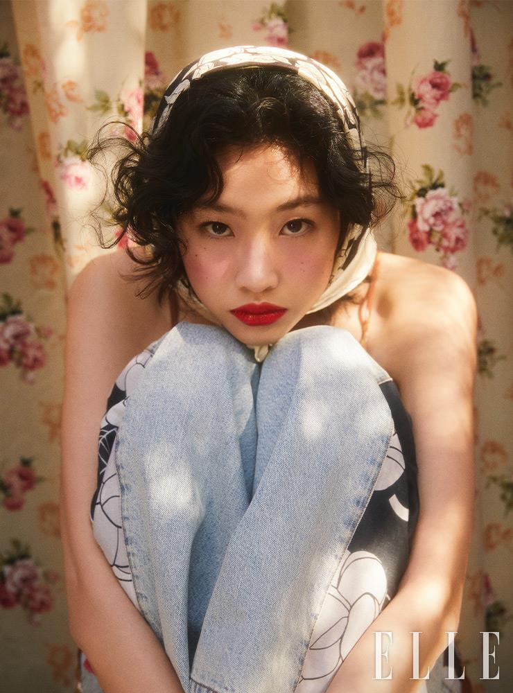 쥬 꽁뜨라스뜨, 270 비브라씨옹으로 양 볼을 감싸듯 둥글려 발라 선명한 코럴 레드빛 치크를 표현하고, 맑은 레드 컬러의 루쥬 코코 블룸, 128 매직을 입술에 여러 번 덧바른다. 사용 제품은 모두 Chanel. 사이드 프린트가 돋보이는 와이드 레그 진은 Chanel. 플로럴 패턴의 스파게티 스트랩 미니드레스는 Reformation from Net-A-Porter. 실크 스카프는 스타일리스트 소장품. 