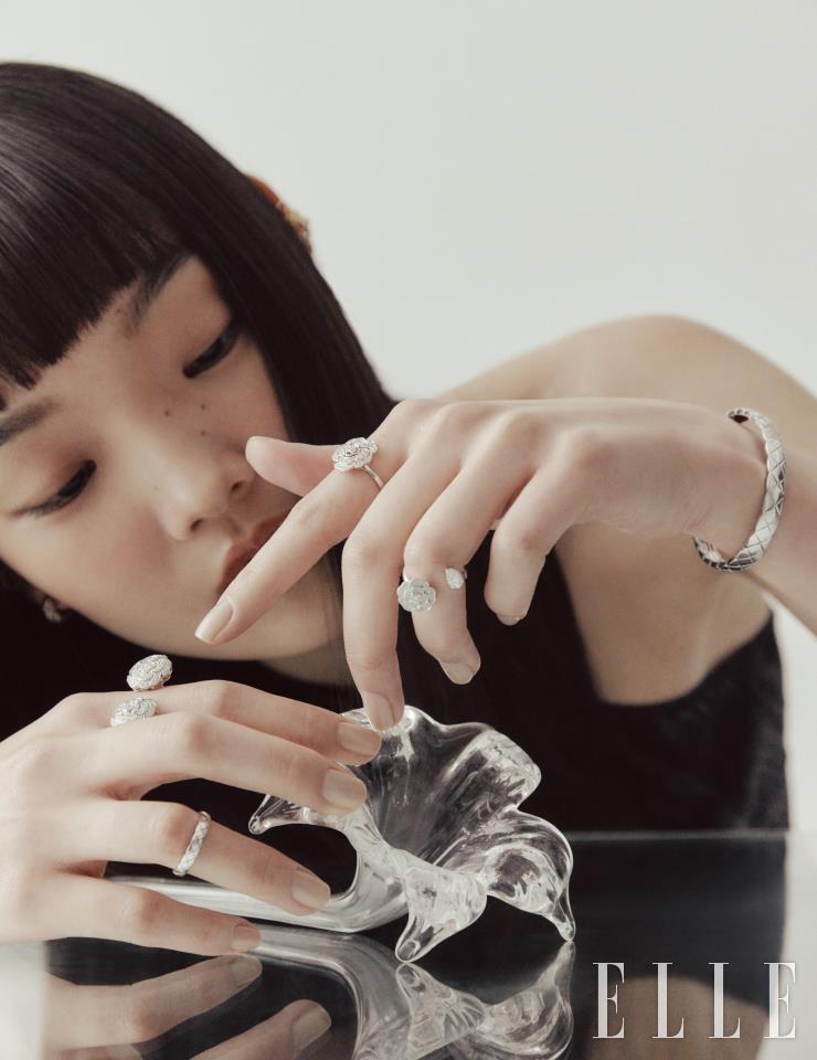 오른손 검지에 낀 꽃송이 모티프의 부통 드 까멜리아 링과 약지의 화이트골드 코코 크러쉬 링, 왼손 검지에 낀 다이아몬드 세팅 화이트골드 부통 드 까멜리아 링, 약지의 까멜리아 프레씨유 링, 퀼팅 모티프의 화이트골드 코코 크러쉬 브레이슬렛, 옐로골드 코코 크러쉬 이어링은 모두 Chanel Fine Jewelry.