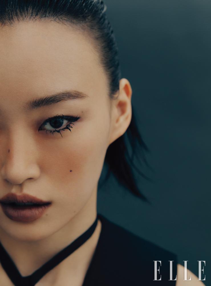 한 치의 흔들림 없이 정면을 응시하는 모습에 나도 모르게 시선을 빼앗긴다. Anastasia Beverly Hills by Sephora, 엠레지 아이섀도 & 프레스트 피그먼트 팔레트, yugo & bk 컬러로 눈두덩 전체에 깊은 음영을 준 뒤, Lancome 그랑디오즈 워터프루프 마스카라를 위아래 속눈썹에 지그재그로 뭉치듯 발라 강렬하게 표현했다. 볼에는 톤다운된 진저 컬러인 Laura Mercier 블러쉬 컬러 인퓨전, 프레스코를 터치했고, 입술은 YSL Beauty 루쥬 르 꾸뛰르 더 슬림, 17 누드 앙토님을 넓게 바른 뒤 18 리버스 레드를 덧발라 스모키하게 마무리했다. 블랙 베스트와 초커는 모두 스타일리스트 소장품. 