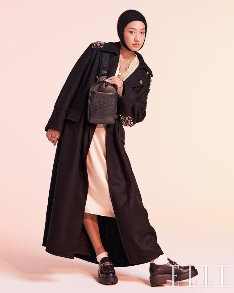  엠보싱 처리된 M 패턴 프린트로 트렌디한 디자인을 완성한 ‘몽블랑 M_Gram 4810 블랙 슬링백’은 Montblanc. 실크 드레스, 코트, 발라클라바, 슈즈는 모두 Miu Miu.