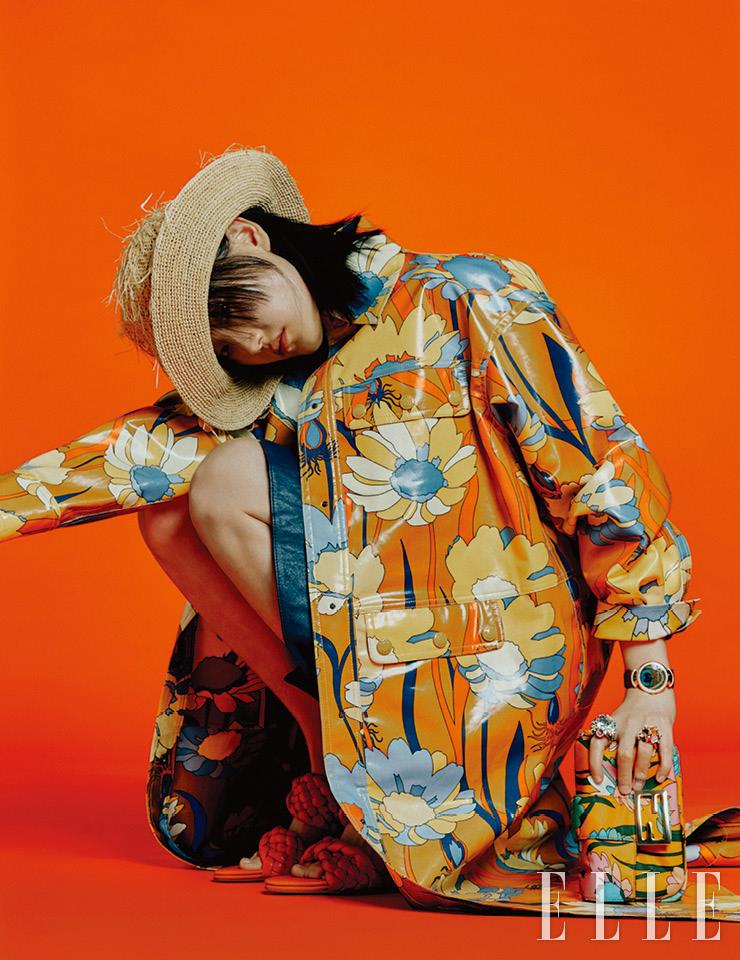 러프한 스트로 디테일의 모자는 가격 미정, Helen Kaminski. 플로럴 패턴의 백은 2백65만원, 코트는 4백69만원, 모두 Fendi. 레더 스커트는 98만원, Coach 1941. 검지에 낀 플라워 장식의 링은 2천6백만원, 약지에 낀 링은 1천1백50만원, 모두 Dior Fine Jewelry. 브라운 레더 스트랩 워치는 3천2백만원대, Bvlgari. 꼬임 디테일의 뮬은 2백7만5천원, Bottega Veneta. 