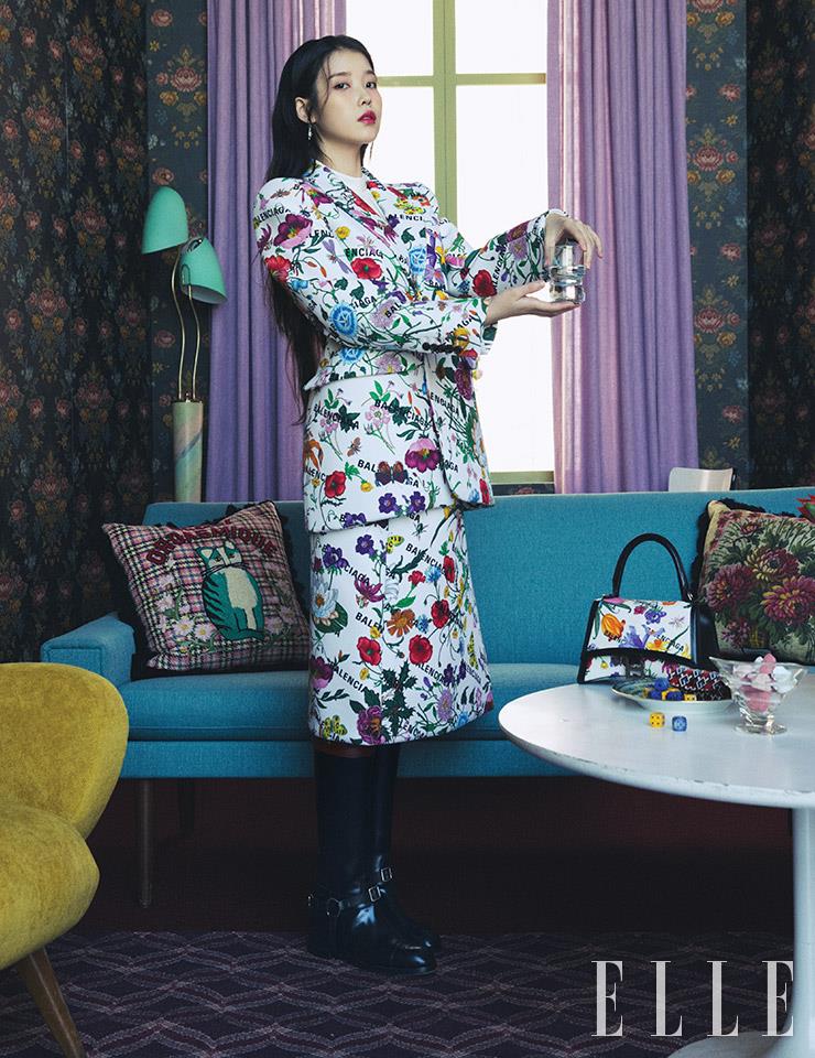 플라워 패턴의 아워글라스 재킷과 스커트, 블라우스, 드롭 이어링, 미니 아워글라스 백, 고양이와 플라워 패턴의 쿠션, 접시와 주사위는 모두 Gucci.