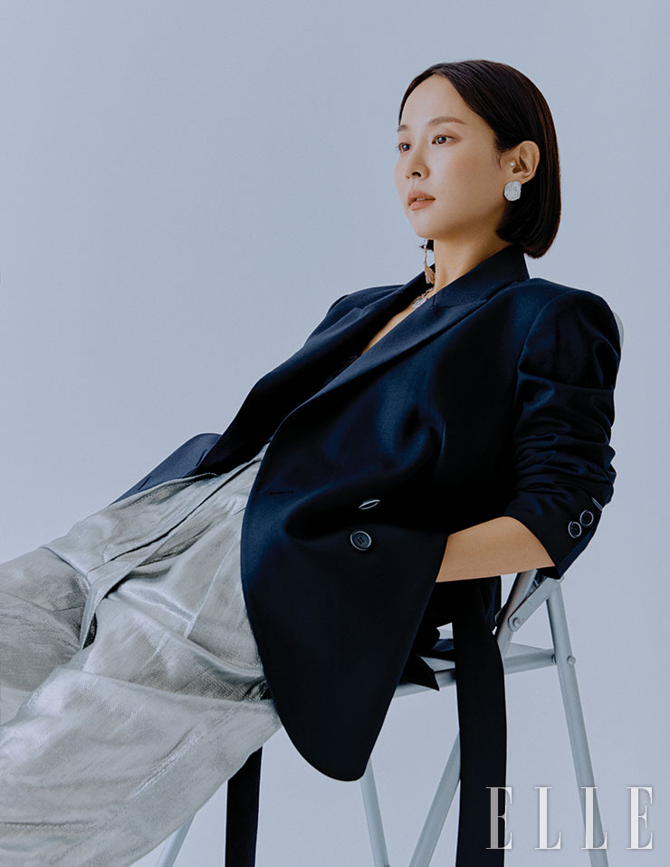 네이비 오버사이즈 재킷은 Ava Molli. 실버 언밸런스 이어링은 Goiu. 실버 소재 배기팬츠는 IRO.