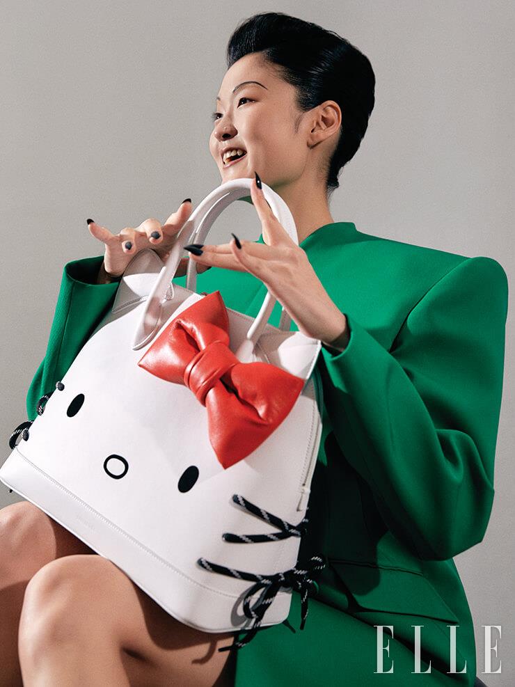 레트로 감성의 그린 컬러 재킷, 미니스커트, ‘헬로 키티 빌 탑 핸들 백’은 모두 Balenciaga.